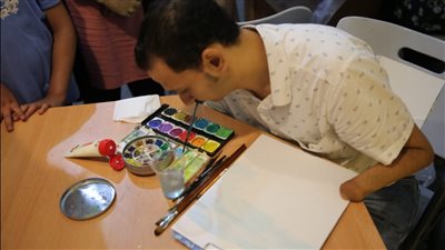 ابن الأزهر.. فنان تشكيلي يرسم بالفم والقدم ومدرس بالجامعة رغم الإعاقة| صور 