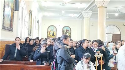 فتاة تسير على عكاز تشارك في جنازة الأنبا كيرلس بقنا 