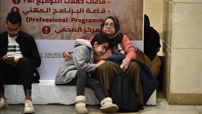 صورة اليوم من معرض الكتاب، ست الحبايب تدفئ طفلتها من البرد