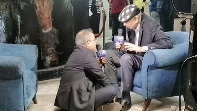 جابر القرموطي يجري لقاءً تليفزيونيًا مع الصحفي محمد العزبي جالسًا على الأرض