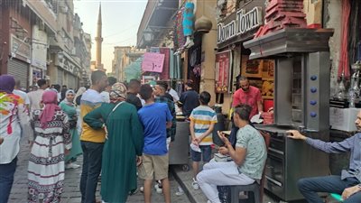 استمتاع زوار شارع المعز بالمأكولات السريعة في ثالث أيام عيد الأضحى (صور)