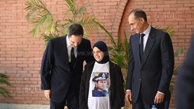 سيدة ترتدي تيشيرت عليه صورة مبارك وتلتقط صور تذكارية مع نجليه