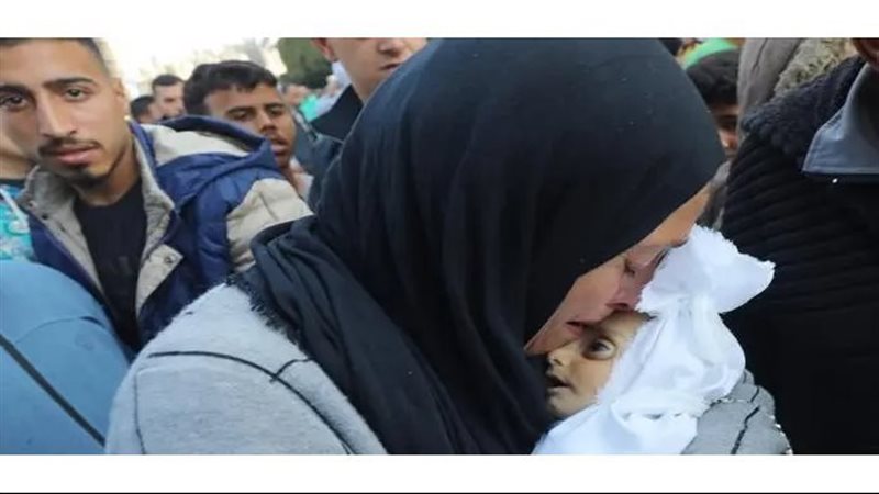 الأم تحمل جثمان الرضيع،