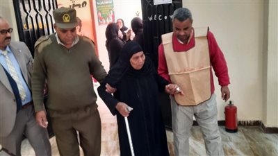قاضي يساعد مسنة على الإدلاء بصوتها في إحدى لجان قنا