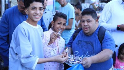 شاب قبطي من ذوي الهمم يوزع الحلوى على المواطنين احتفالا بعيد الفطر في الأقصر (صور)