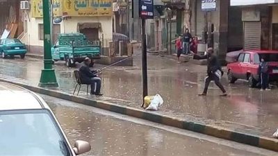 مواطن بالمنيا يتحدى الأمطار والعاصفة الترابية بصنارة صيد في الشارع 