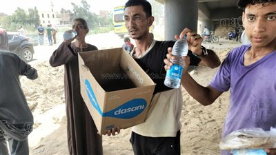 شاب يوزع المياه والطعام على المشاركين في البحث عن جثامين ضحايا معدية أبو غالب (فيديو وصور)