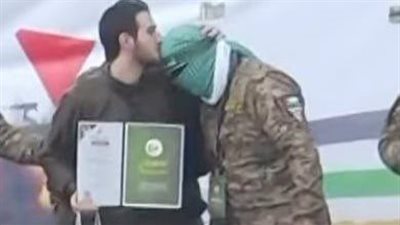 أسير إسرائيلي يقبل رؤوس مقاتلين من غزة على منصة التسليم بالنصيرات