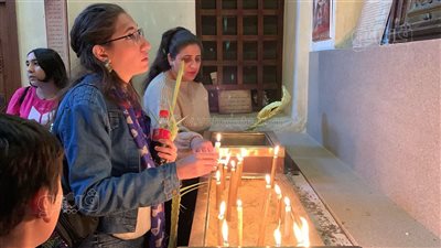 الزوار يشعلون الشموع، مظاهر الاحتفال بـ أحد السعف داخل مجمع الأديان (فيديو)