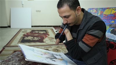 عندما تتحول الإعاقة إلى معجزة.. رضا فضل فنان تشكيلي وأستاذ جامعي بلا يدين | فيديو وصور  
