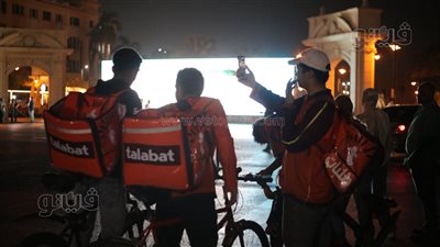 وسط كفاحهم، عمال الدليفري يتوقفون أمام الشاشات العملاقة لمشاهدة افتتاح المتحف الكبير (صور)