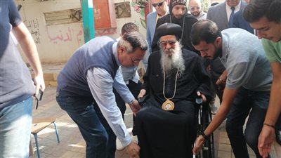 على كرسي متحرك، مطران الفيوم يدلي بصوته في انتخابات مجلس النواب (صور)