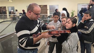 مشهد استثنائي، شاب يعلم أطفال معرض الكتاب فنون العزف على الكمان مجانا (صور)