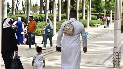 دلع البنات.. أب يحمل طفلته فوق ظهره وآخر يحمل حقيبتها بحديقة الأزهر | صور 