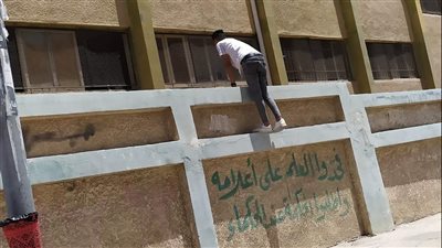 شخص يعتلي سور مدرسة بالعريش لنقل الإجابة لطالبة | صور