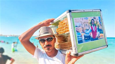 هكمل رحلة كفاحه.. زميل أشيك بائع فريسكا يتجول برفقة صوره على شواطئ مطروح | فيديو